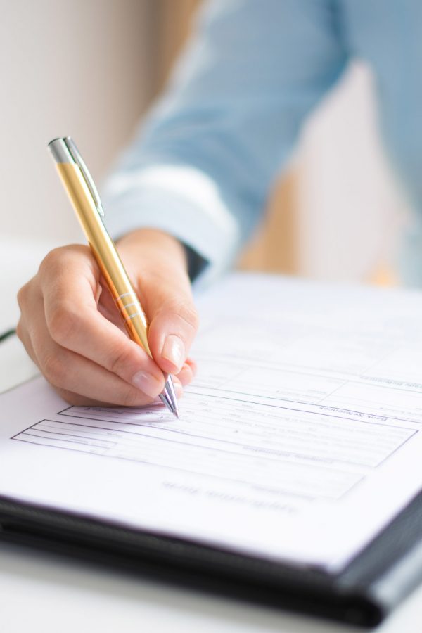 Closeup of business woman making notes in document. Entrepreneur sitting at desk and writing. Paperwork concept. Cropped view.