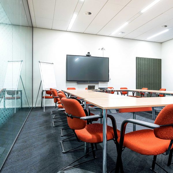 The conference room interior of a modern office with white walls and a monitor